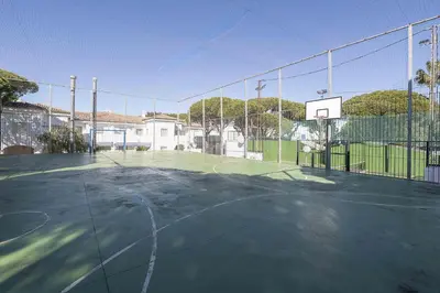 an empty tennis court with a basketball hoop at La Almadraba in Novo Sancti Petri