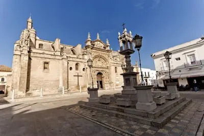 an old church with a statue in front of it at Cruces by LiveWork in El Puerto de Santa María