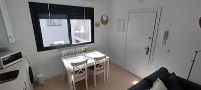 a small white kitchen with a table and chairs at Cruces by LiveWork in El Puerto de Santa María