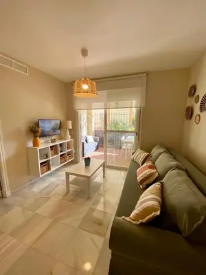 a living room with a green couch and a table at Playa Ballena Apartment in Chipiona