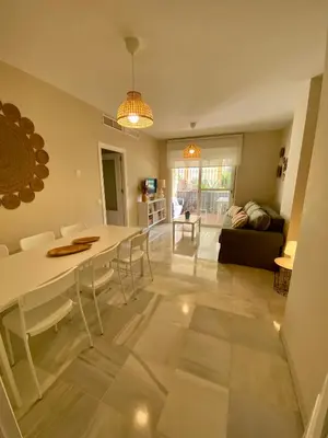 a dining room and living room with a table and chairs at Playa Ballena Apartment in Chipiona