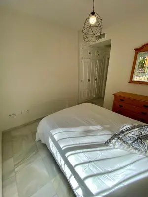 a bedroom with a large bed and a dresser at Playa Ballena Apartment in Chipiona