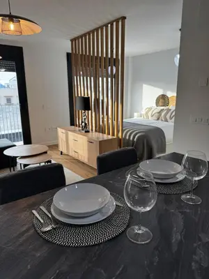 a dining table with plates and wine glasses on it at Ático Roomy in Jerez de la Frontera