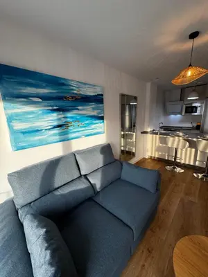 a living room with a blue couch and a kitchen at Estudio Roomy Jerez in Jerez de la Frontera
