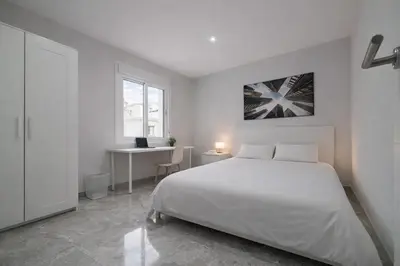 a white bedroom with a bed and a desk at Apartamento Luz de Cádiz in Cádiz