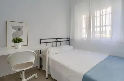 a bedroom with a bed and a desk and a chair at Apartamento Playa de Cádiz in Cádiz