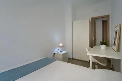 a white bedroom with a white bed and a desk at Apartamento Playa de Cádiz in Cádiz