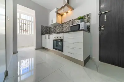 a kitchen with white cabinets and a tile wall at Apartamento Luz de Gadir in Cádiz
