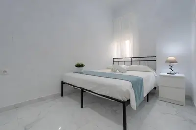 a white bedroom with a bed with a blue blanket at Apartamento Luz de Gadir in Cádiz