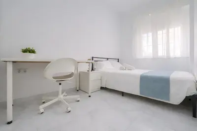 a bedroom with a bed and a desk and a chair at Apartamento Luz de Gadir in Cádiz