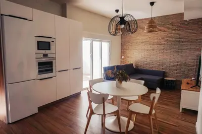 a kitchen and a living room with a table and chairs at Apartamento en pleno centro de Jerez con patio privado in Jerez de la Frontera