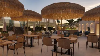a restaurant with tables and chairs and large straw umbrellas at Gran Hotel Luna de Cádiz in Cádiz