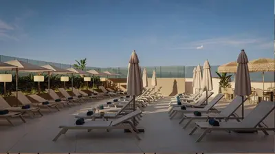 a row of lounge chairs and umbrellas on a beach at Gran Hotel Luna de Cádiz in Cádiz