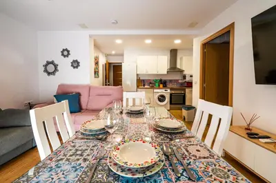 a dining room table with plates and glasses on it at YourHouse Apartamentos Andasol 1D in Chipiona