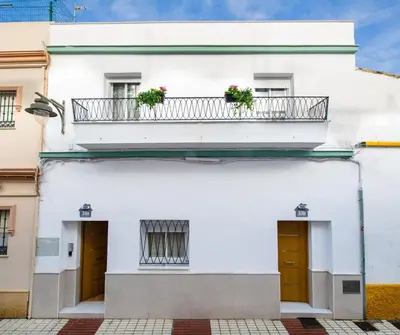 a white building with two balconies with flowers on it at YourHouse Apartamentos Andasol 1D in Chipiona