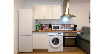 a kitchen with a washing machine and a microwave at YourHouse Apartamentos Andasol 1 I in Chipiona