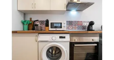 a kitchen with a washing machine and a microwave at YourHouse Apartamentos Andasol 1 I in Chipiona