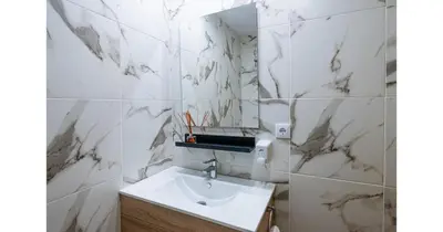 a bathroom with white marble walls and a sink at YourHouse Apartamentos Andasol 1 I in Chipiona