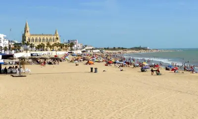 a group of people on a beach near the ocean at YourHouse Apartamentos Andasol BB in Chipiona