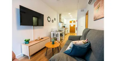 a living room with a couch and a tv on a wall at YourHouse Apartamentos Andasol BB in Chipiona