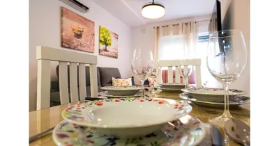 a dining room table with glasses and plates on it at YourHouse Apartamentos Andasol BB in Chipiona