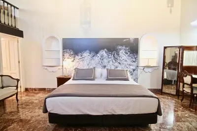 a bedroom with a large bed with a painting on the wall at El Palacete del Puerto in El Puerto de Santa María