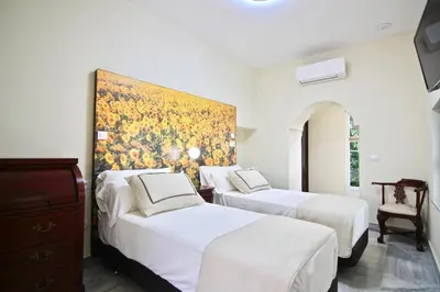 two beds in a room with a painting on the wall at El Palacete del Puerto in El Puerto de Santa María
