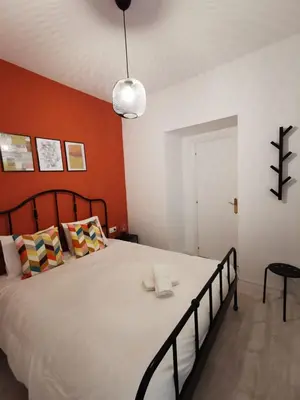 a bedroom with a large bed with an orange wall at CDZ - Buenos Aires en Cádiz in Cádiz