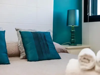 a bedroom with a bed with blue pillows and a lamp at Villa Sol Sal free parking by Staycare in Rota