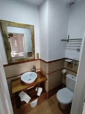 a bathroom with a sink and a toilet and a mirror at Hotel Pozo Rey by Youroom in Chipiona