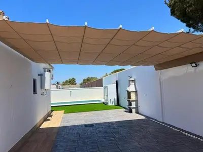 a patio with a large wooden umbrella on a white building at ChiclanaVillage in Chiclana de la Frontera
