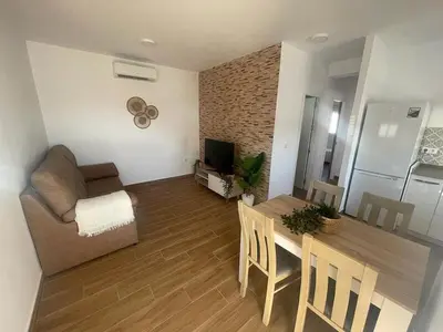 a living room with a table and a couch and a kitchen at ChiclanaVillage in Chiclana de la Frontera