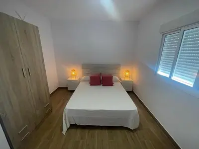 a white bedroom with a large bed with red pillows at ChiclanaVillage in Chiclana de la Frontera
