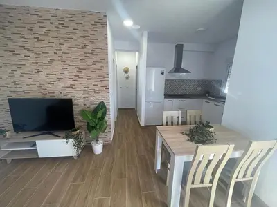a kitchen and living room with a table and a television at ChiclanaVillage in Chiclana de la Frontera