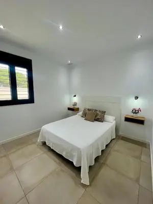 a white bedroom with a bed and a window at ChiclanaVillage in Chiclana de la Frontera