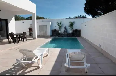 a swimming pool with two lounge chairs and a table at ChiclanaVillage in Chiclana de la Frontera