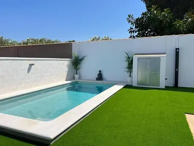 a backyard with a swimming pool and green grass at ChiclanaVillage in Chiclana de la Frontera
