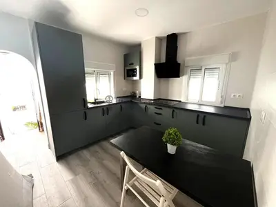 a kitchen with a black counter top and a table at Apartamento Centro de Rota La Costilla in Rota