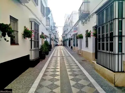 an empty alley with buildings and potted plants at Apartamento Centro de Rota La Costilla in Rota
