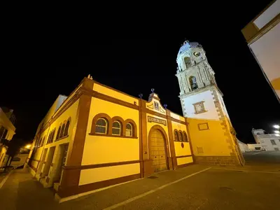 a yellow building with a clock tower at night at Apartamento Centro de Rota La Costilla in Rota