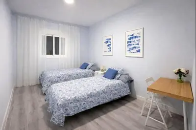 a bedroom with two beds and a desk and a table at Apartamento Centro de Rota La Costilla in Rota