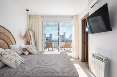 a bedroom with a bed with a television and a balcony at Casa junto al mar con piscina 45 in Conil de la Frontera
