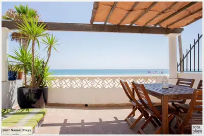 a patio with a table and chairs and the ocean at Family Friendly 2BDR Unit in Rota - Playa in Rota