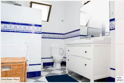 a bathroom with a toilet and blue and white tiles at Family Friendly 2BDR Unit in Rota - Playa in Rota