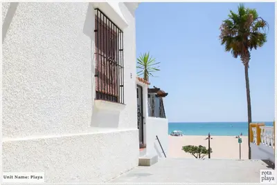 a white building with a window and a beach at Family Friendly 2BDR Unit in Rota - Playa in Rota