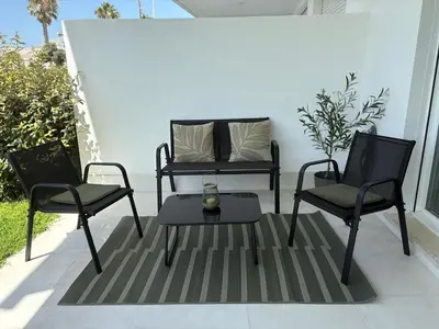 two chairs and a table on a patio at Nuevo bajo con gran jardín en primera línea playa in Chipiona