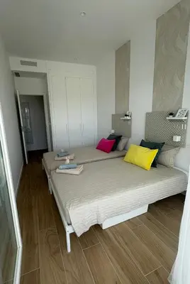 a bedroom with a bed with colorful pillows on it at Nuevo bajo con gran jardín en primera línea playa in Chipiona