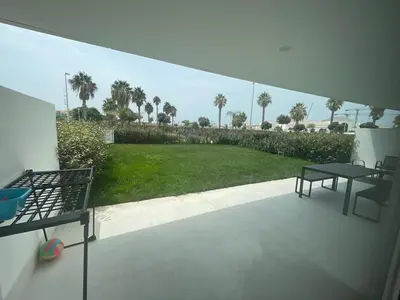 a balcony with a table and a view of a yard at Nuevo bajo con gran jardín en primera línea playa in Chipiona