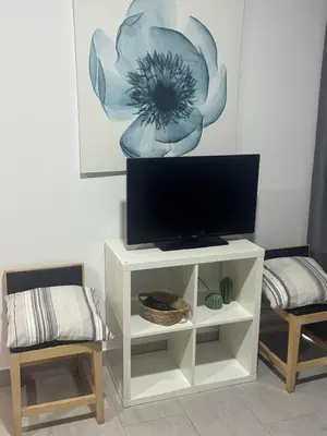 a white entertainment center with a tv and two chairs at Austria 03 in Lebrija