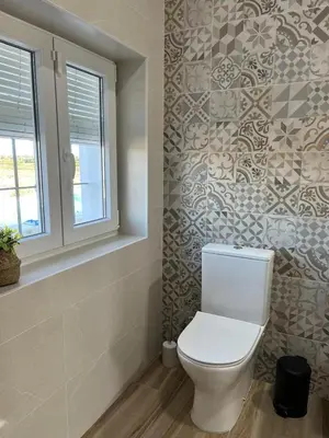 a bathroom with a toilet and a window and tiles at Los Granainos in El Guijo